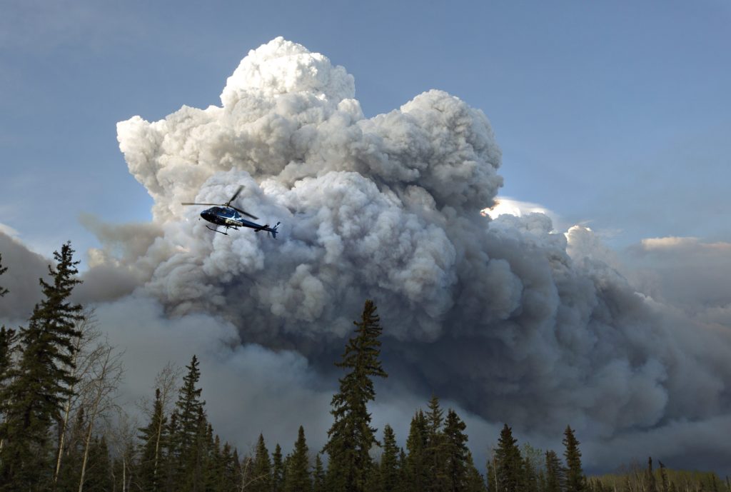 A helicopter flies past a wildfire in Fort McMurray, Alta., on Wednesday May 4, 2016. The wildfire has already torched 1,600 structures in the evacuated oil hub of Fort McMurray and is poised to renew its attack in another day of scorching heat and strong winds.THE CANADIAN PRESS/Jason Franson