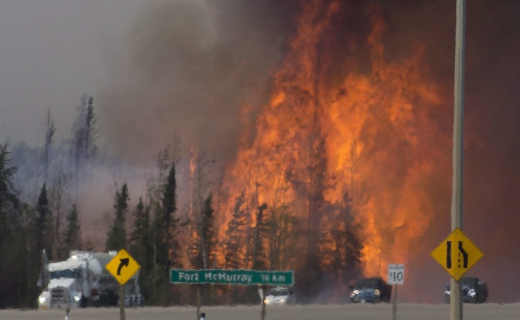 Heat waves are seen as cars and trucks try and get past a wild fire 16km south of Fort McMurray on highway 63 Friday, May 6, 2016. THE CANADIAN PRESS/Jonathan Hayward