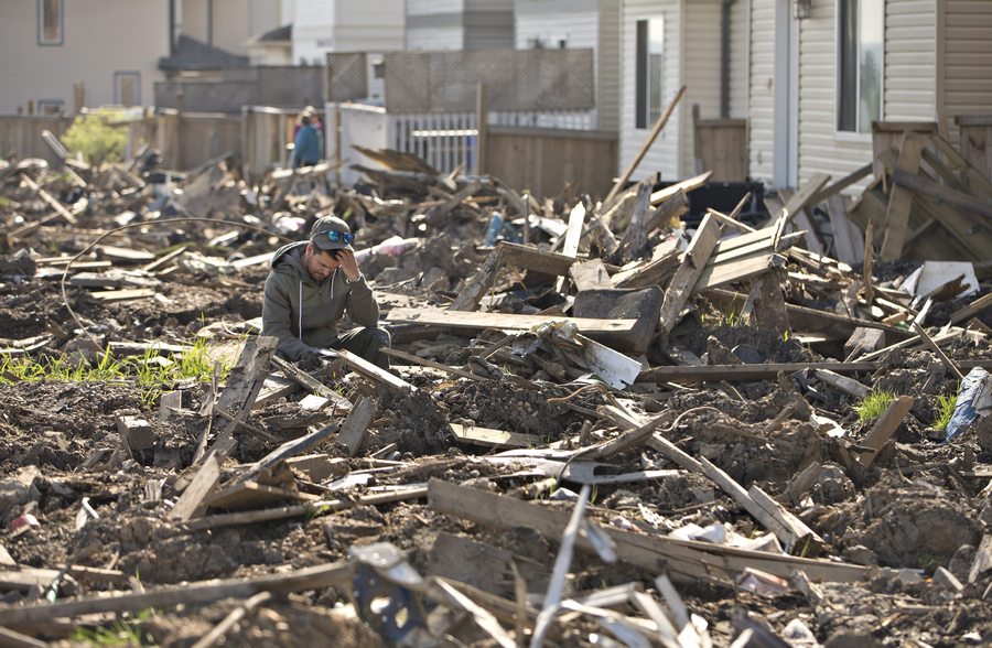 A resident of the Timberlea neighbourhood sits amoung the rubble in Fort McMurray, Alta, on Thursday June 2, 2016. Residents are slowly being allowed back into their homes. THE CANADIAN PRESS/Jason Franson