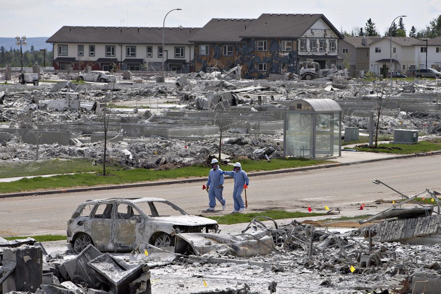Workers put out markers around a devastated area of Timberlea in Fort McMurray Alta, on Thursday, June 2, 2016. Members of the community are slowly being allowed back into their homes. THE CANADIAN PRESS/Jason Franson