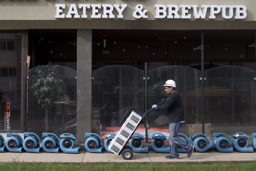 Erlin Rivera wheels supplies past fans as he works to clean a pub in Fort McMurray Alta, on Friday, June 3, 2016. Members of the community are now being allowed back into their homes. THE CANADIAN PRESS/Jason Franson