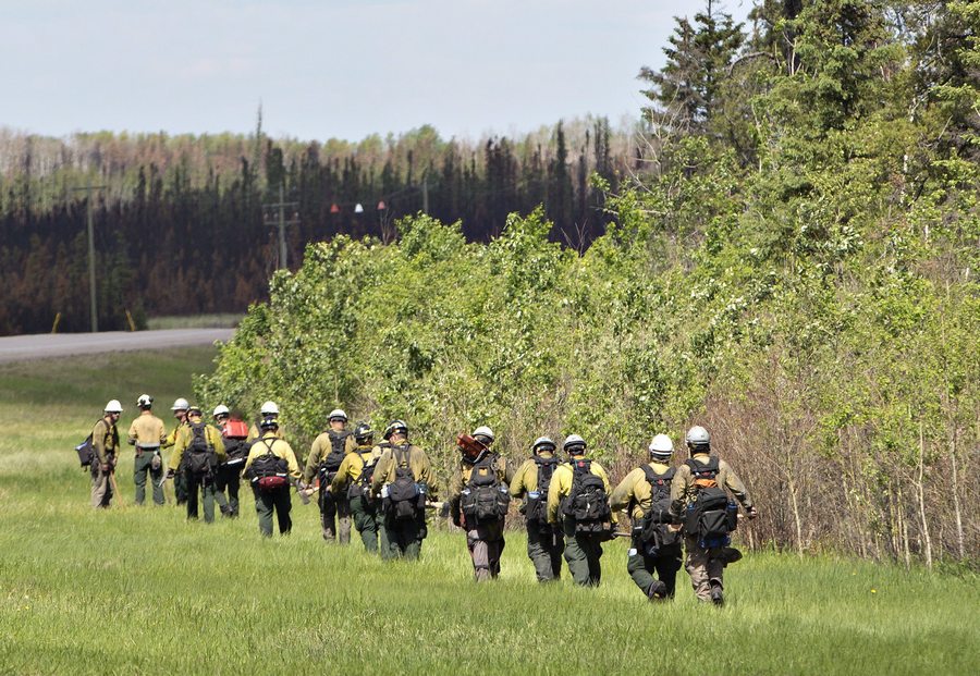 Fire crews work the tree line in Anzac near Fort McMurray, Alta., on Saturday, June 4, 2016. Members of the community are now being allowed back into their homes. THE CANADIAN PRESS/Jason Franson
