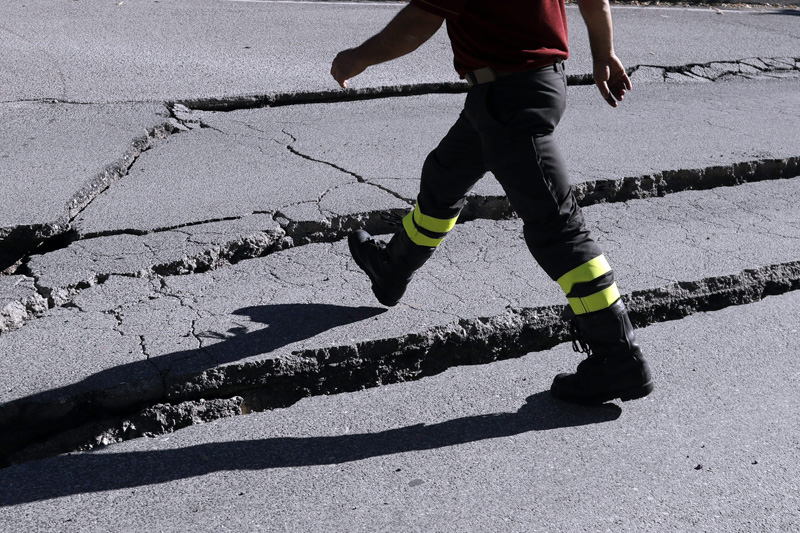 A firefighter steps over cracks in a road in Norcia, central Italy, after an earthquake with a preliminary magnitude of 6.6 struck central Italy, Sunday, Oct. 30, 2016. Central Italy was hit by another powerful earthquake Sunday, toppling buildings that had recently withstood other major quakes and sending panicked residents back into the streets, but causing no immediate loss of life. (AP Photo/Gregorio Borgia)
