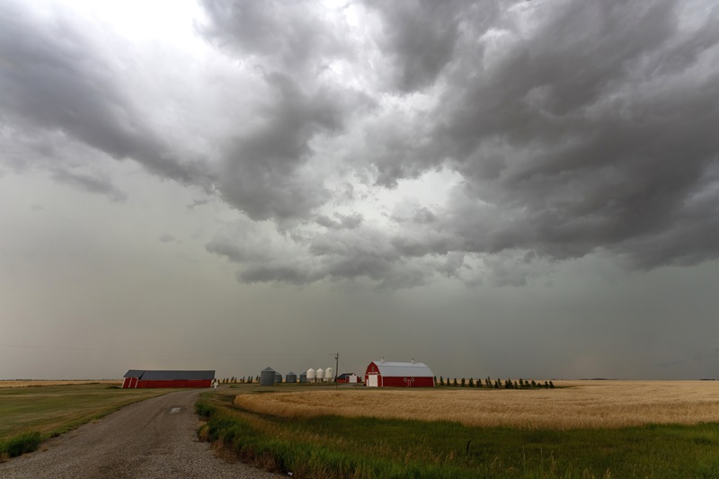 Dark storm clouds are gathering over a farm in the canadian prairies