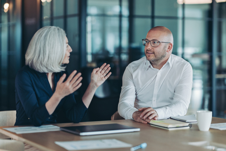Mature businesswoman talking to a colleague alternate text for this image