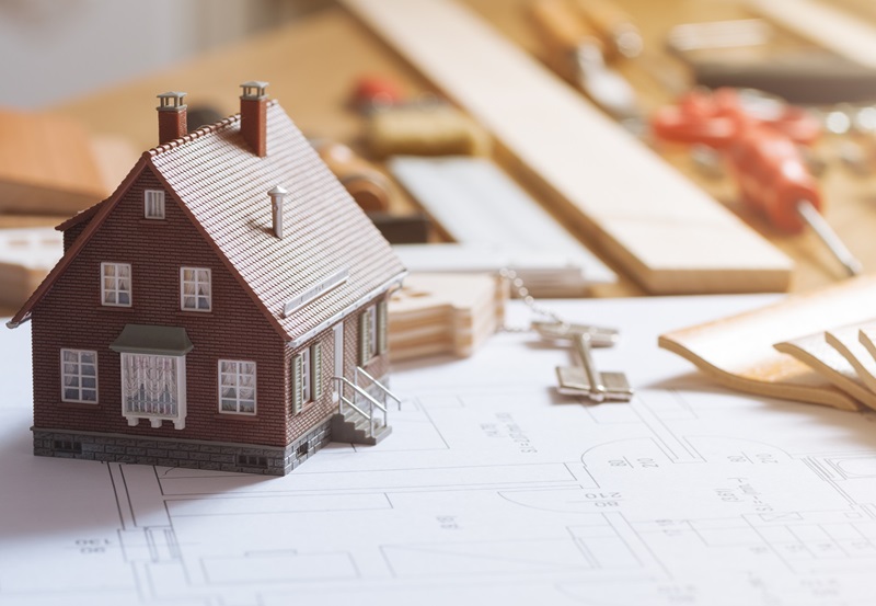 Construction and home renovation concept, model house, work tools, house keys and draft project on a desktop