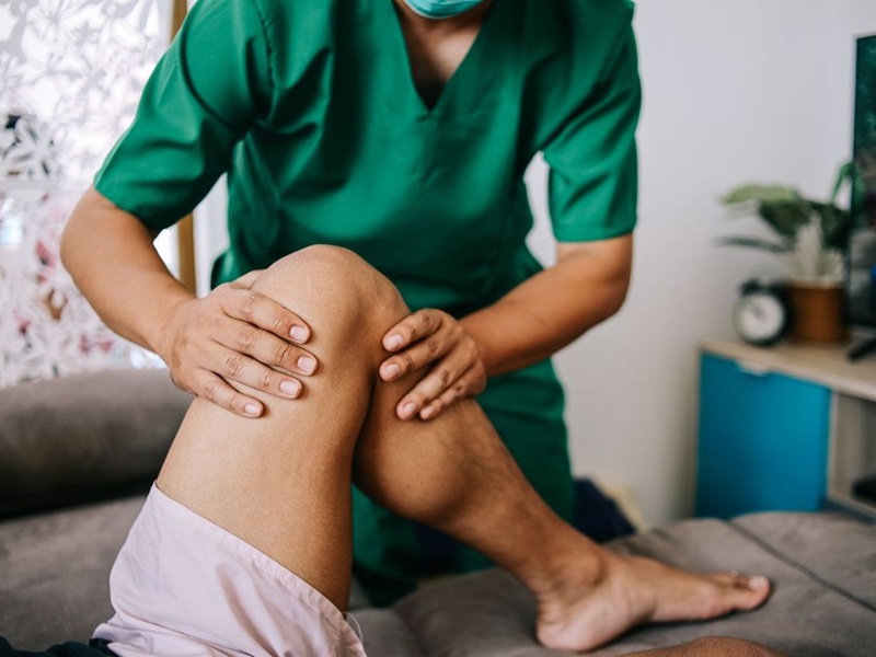 Physiotherapist treating leg of patient at home
