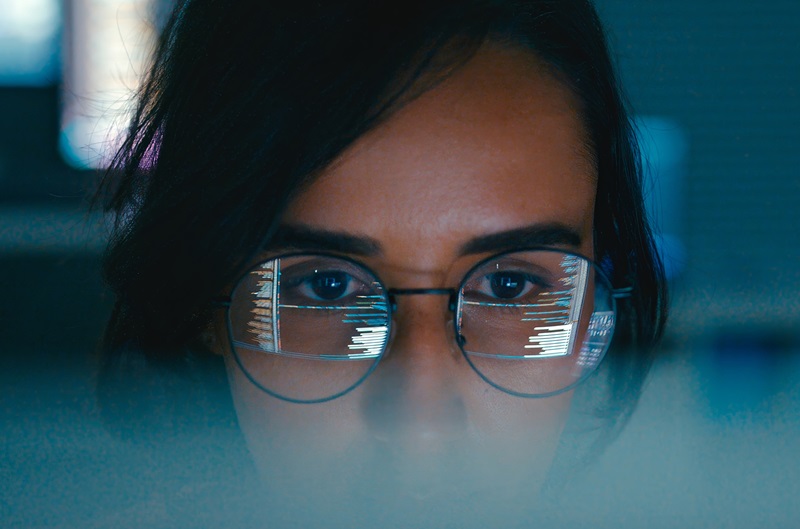 Closeup of Female computer programmer works on complex software development tasks at her home office late into the night. Software developer, artificial intelligence and programming concept.