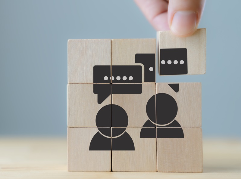 Consumer feedback concept. Customer satisfaction evaluation to improve and develop product and service. Customer centric. Hand puts wooden cubes with "feedback" icon on grey background ,copy space.