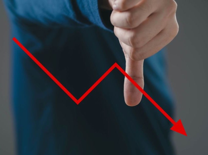 Businessman shows thumbs down on a financial graph